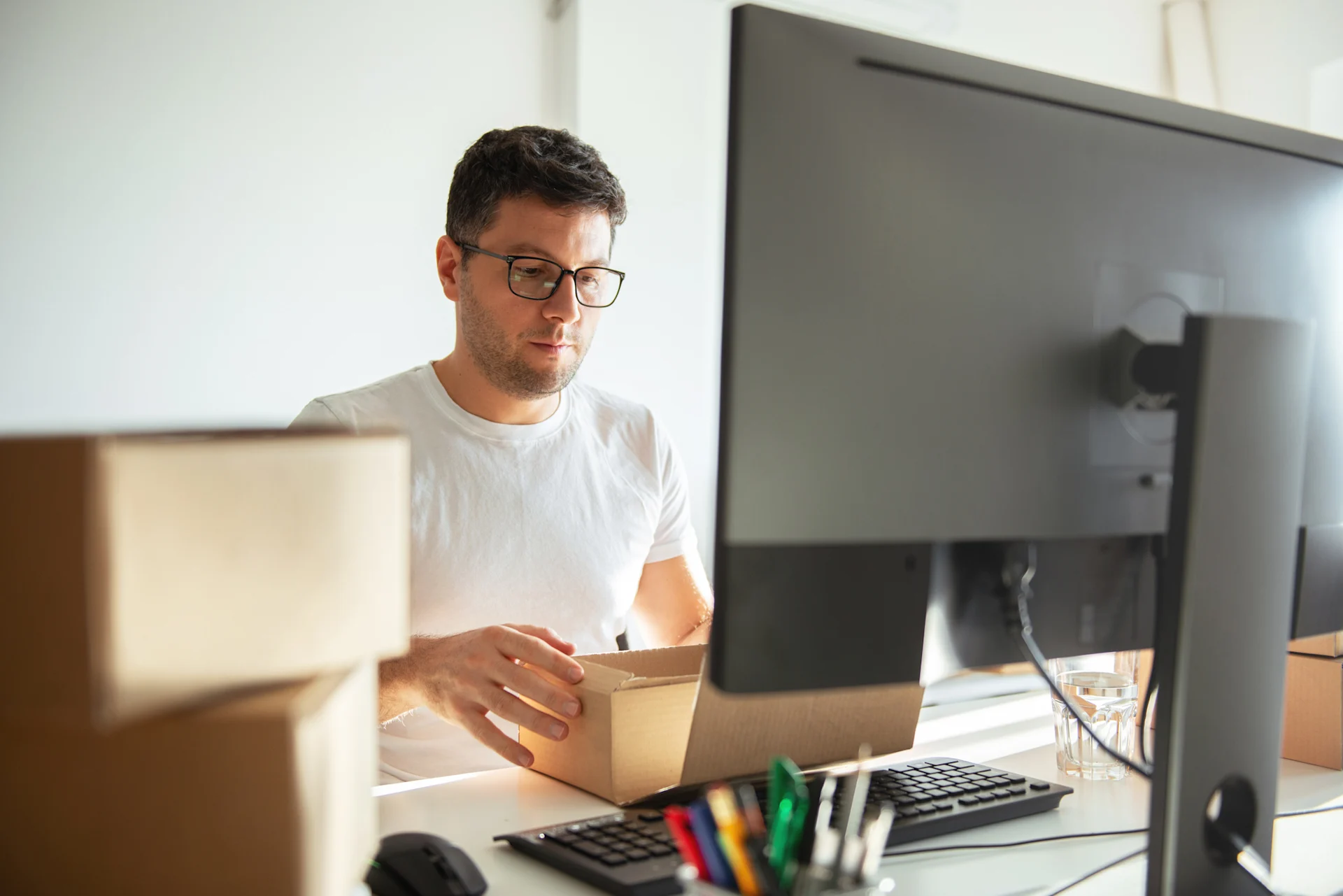 Man packing parcel while at laptop