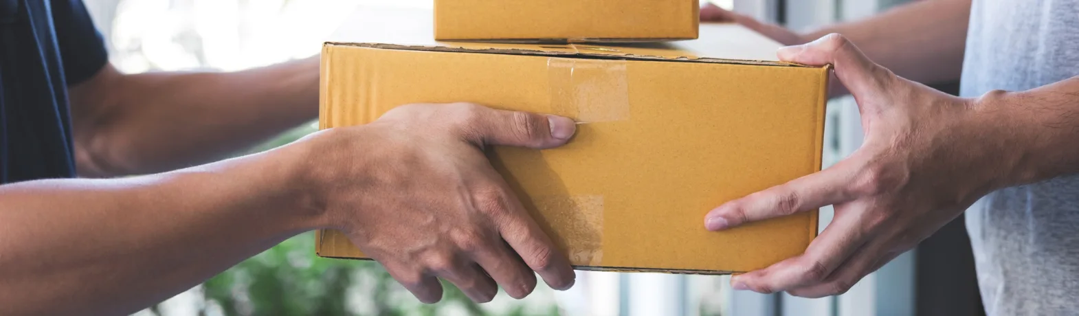 Two people exchanging a parcel box on a doorstep.
