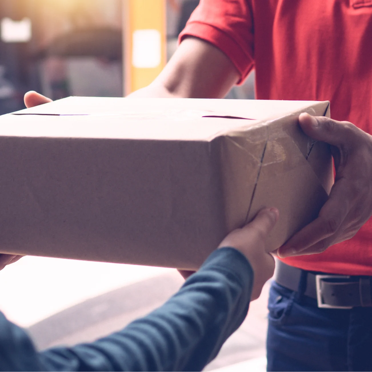 Delivery man in red polo top handing parcel over to customer